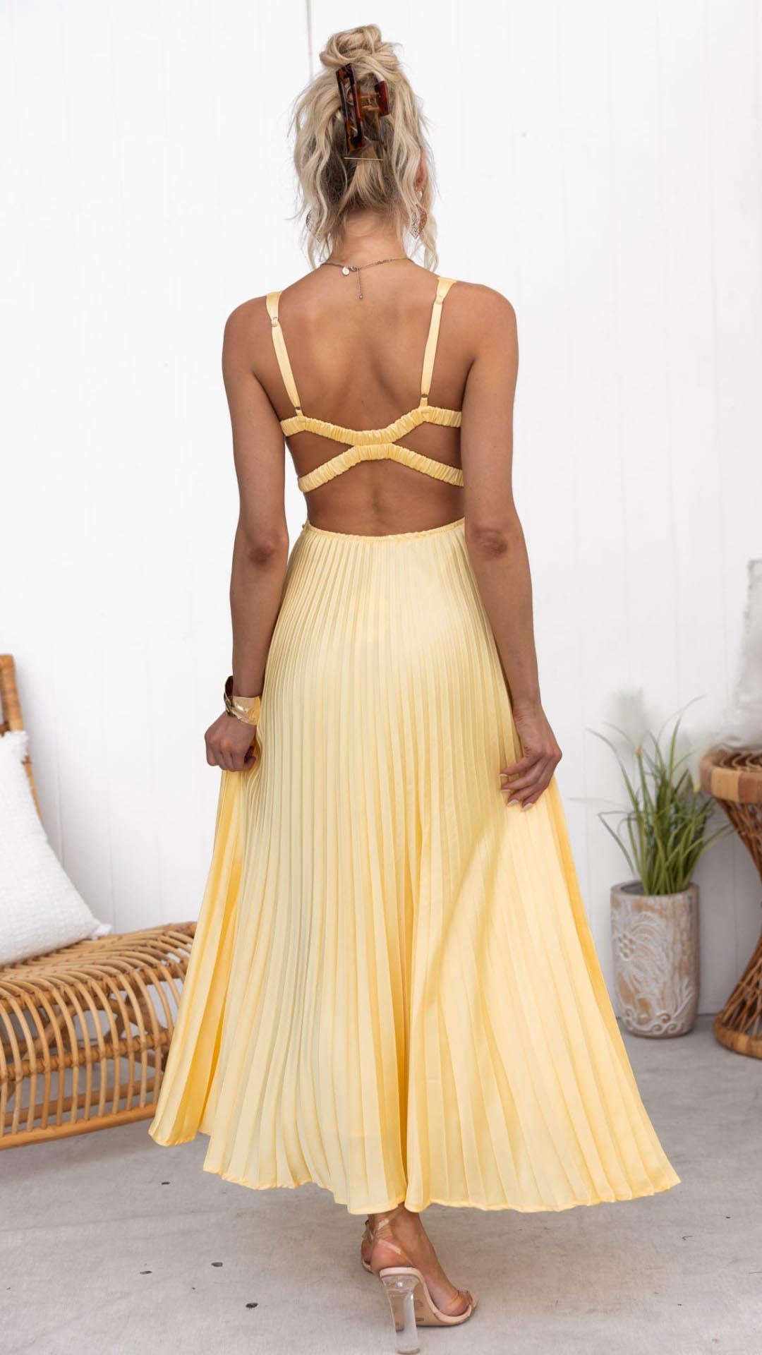 Rear view of pleated V neck maxi dress showing open back and flowing skirt