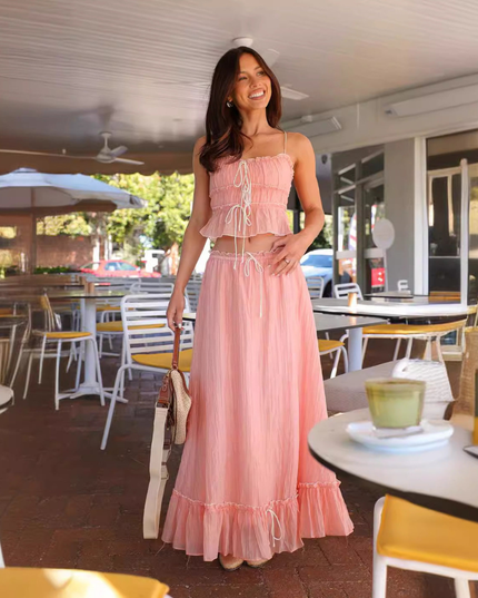Pink summer maxi skirt set with ruched crop top and flowing skirt in a cafe setting