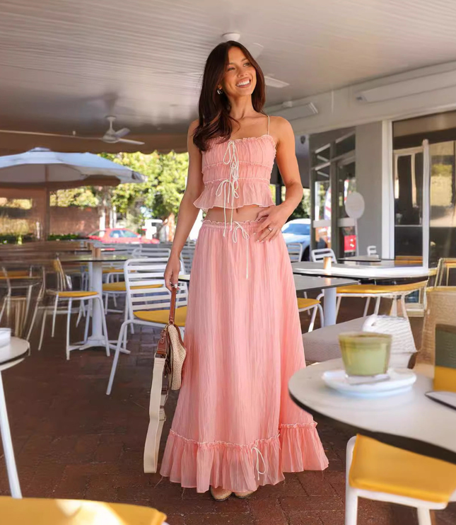Pink summer maxi skirt set with ruched crop top and flowing skirt in a cafe setting