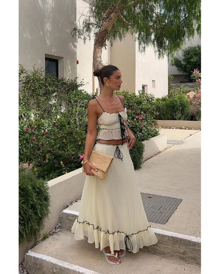 Cream summer maxi skirt set with black trim, spaghetti straps, and ruffled hem outdoors