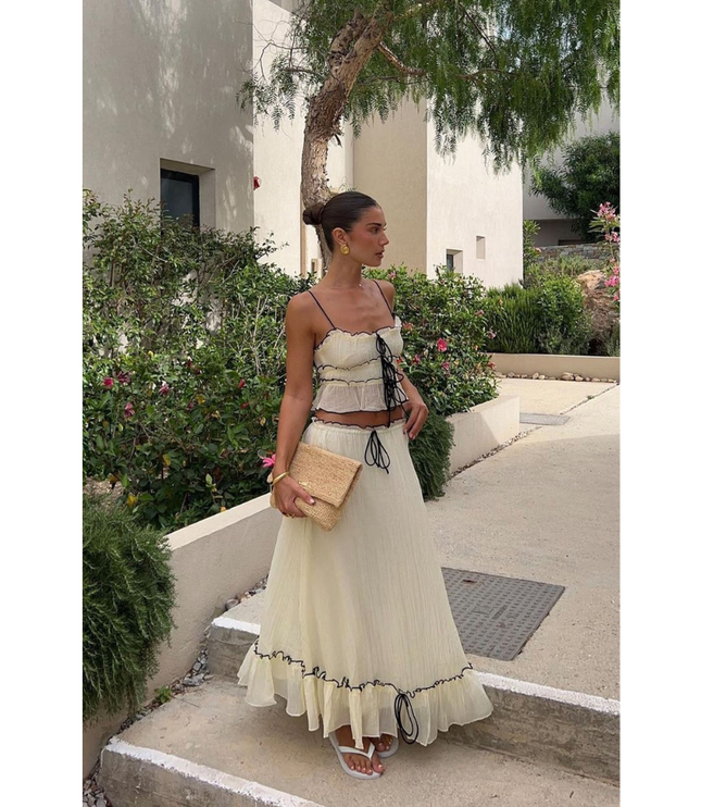 Cream summer maxi skirt set with black trim, spaghetti straps, and ruffled hem outdoors