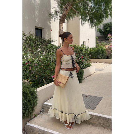 Cream summer maxi skirt set with black trim, spaghetti straps, and ruffled hem outdoors
