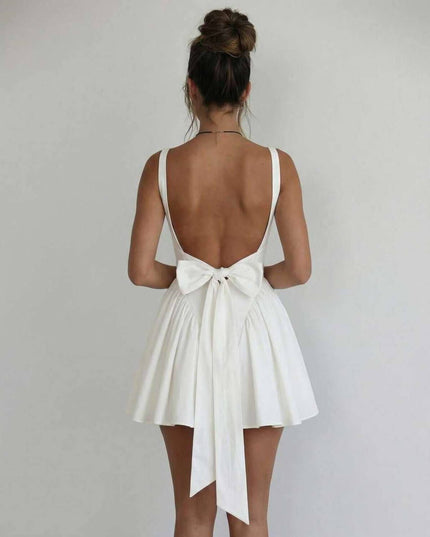 Back view of white mini dress with low open back and bow tie detail for wedding guest attire