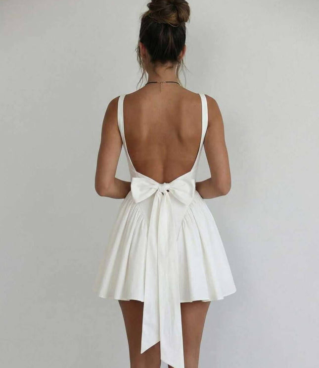 Back view of white mini dress with low open back and bow tie detail for wedding guest attire
