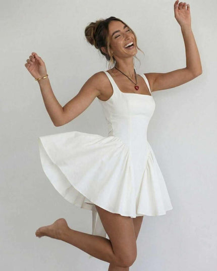 Woman wearing white square neck mini dress twirling to show full flared skirt and open back