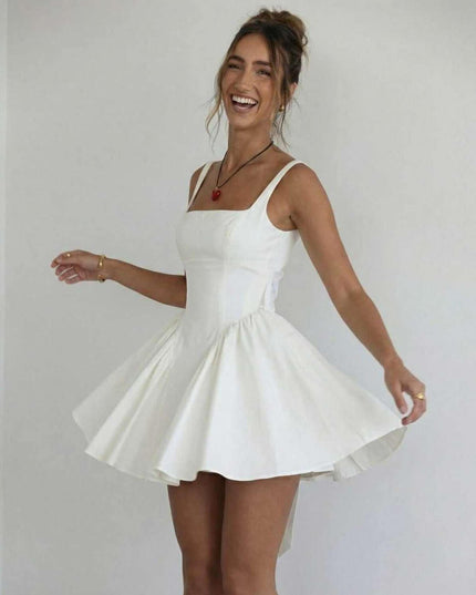 White wedding guest mini dress with square neckline and voluminous skirt in a playful pose