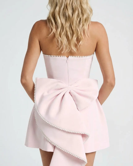 Back view of pink strapless dress with pearl trim and large bow detail