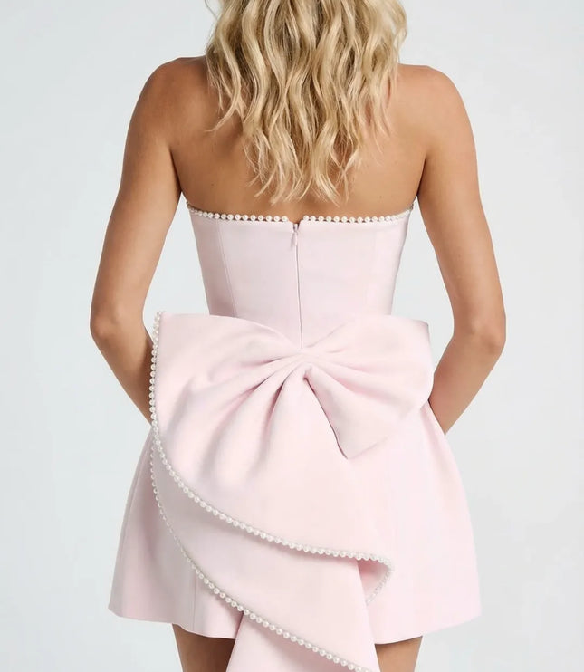 Back view of pink strapless dress with pearl trim and large bow detail