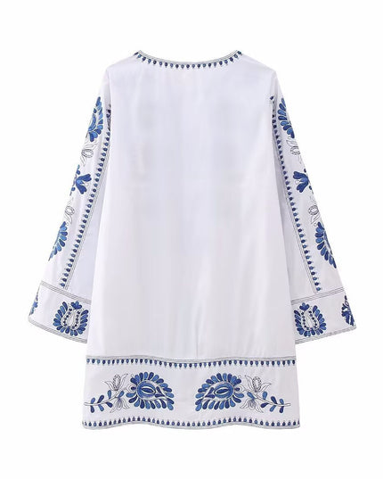 Back view of white mini dress with blue embroidered border details and relaxed fit
