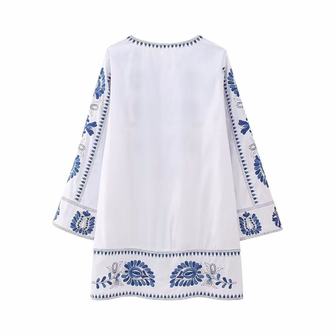 Back view of white mini dress with blue embroidered border details and relaxed fit
