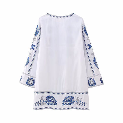 Back view of white mini dress with blue embroidered border details and relaxed fit