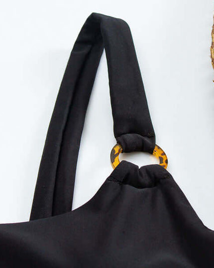 Close-up of black swimsuit strap and tortoiseshell ring detail on one piece swimsuit