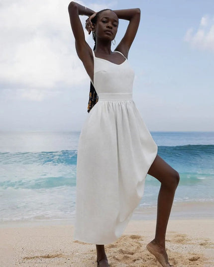 White linen maxi dress with one-shoulder tie strap and flowing skirt on the beach