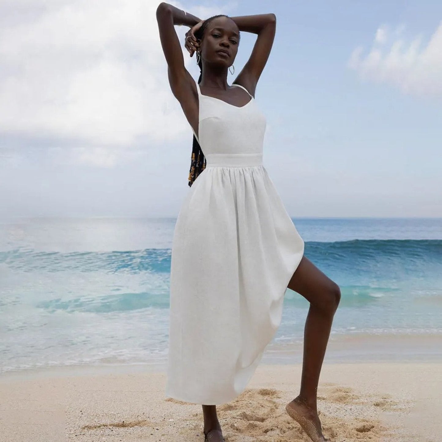 White linen maxi dress with one-shoulder tie strap and flowing skirt on the beach