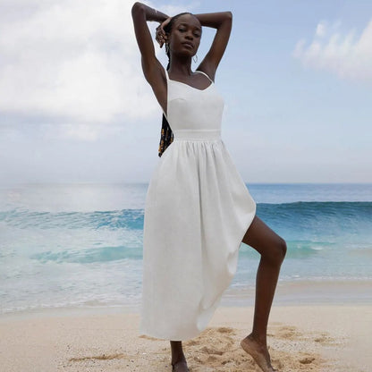 White linen maxi dress with one-shoulder tie strap and flowing skirt on the beach