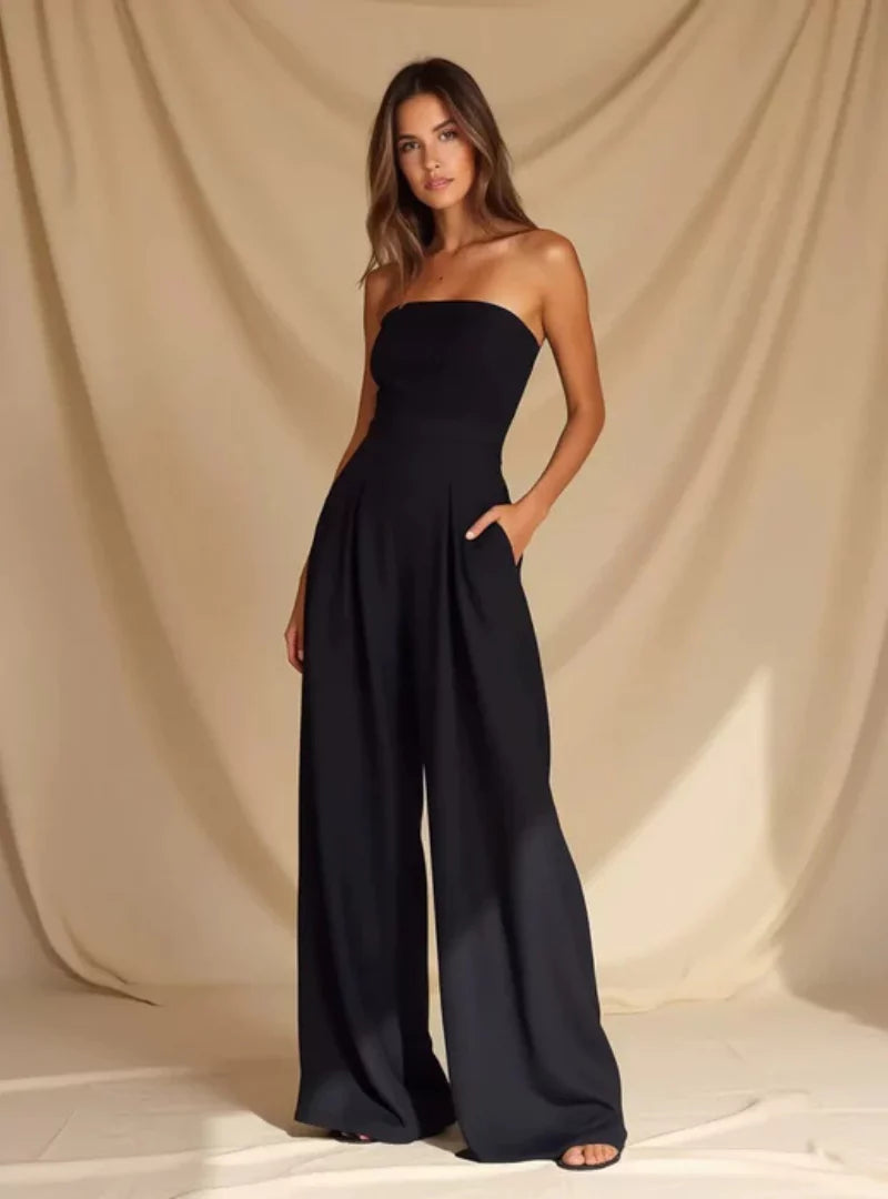Back view of a navy strapless wide leg jumpsuit with smooth fitted top and flowing pants