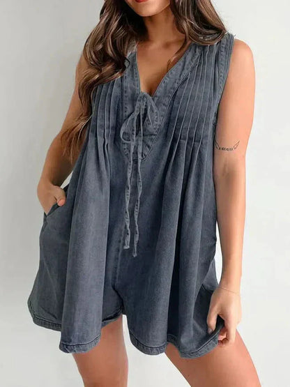 Dark washed mini denim romper for women with V-neck tie front, pleated bodice, and relaxed shorts