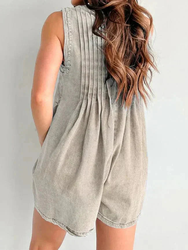 Back view of beige women's denim romper with soft pleats, sleeveless shoulders, and mini length