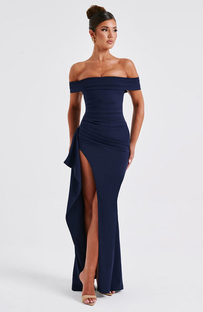Front view of navy off shoulder maxi dress with ruched bodice, high slit, and fitted shape
