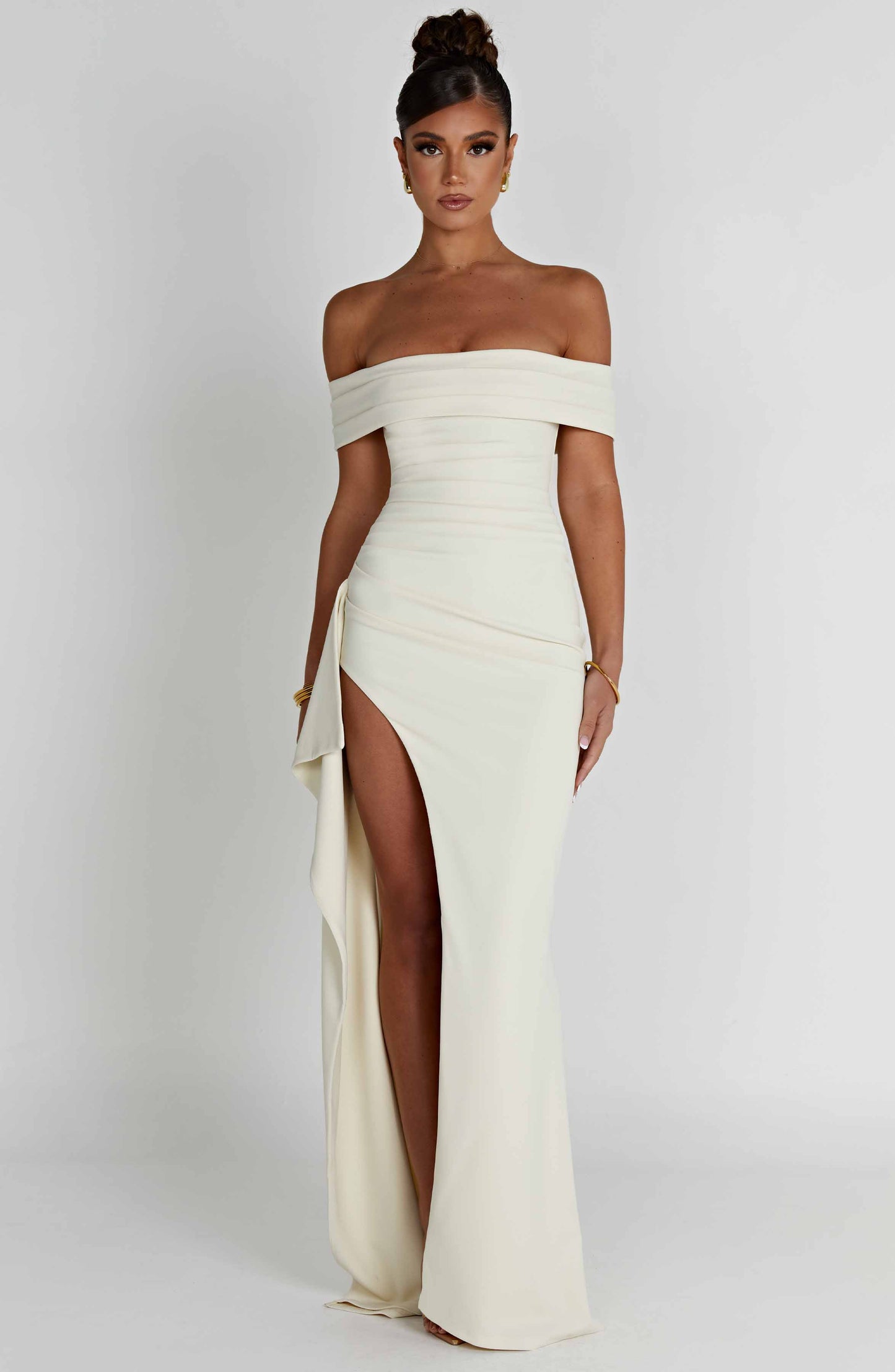 Front view of cream off shoulder formal maxi dress with fitted waist and slit