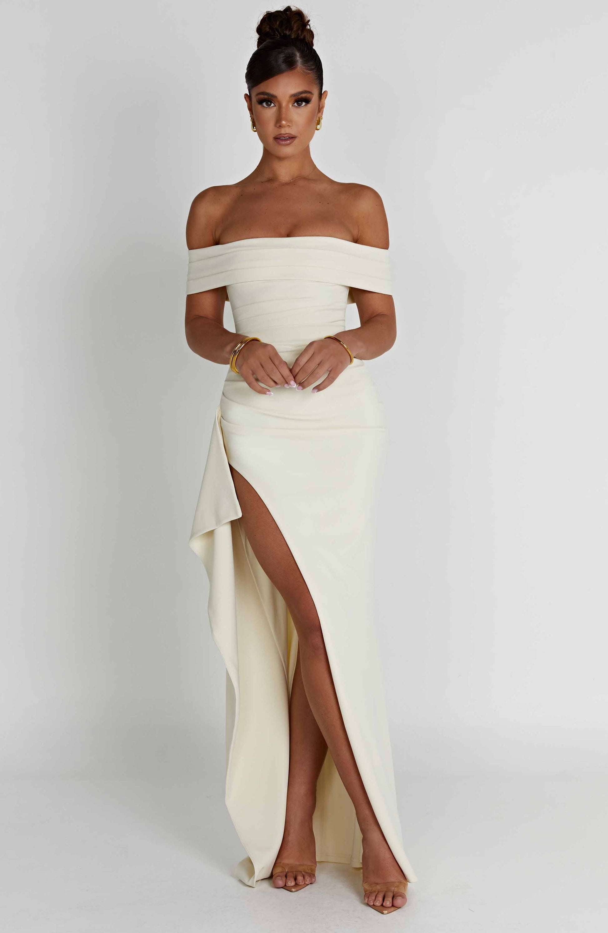 Cream off shoulder maxi dress with high slit and flowing skirt, angled front view