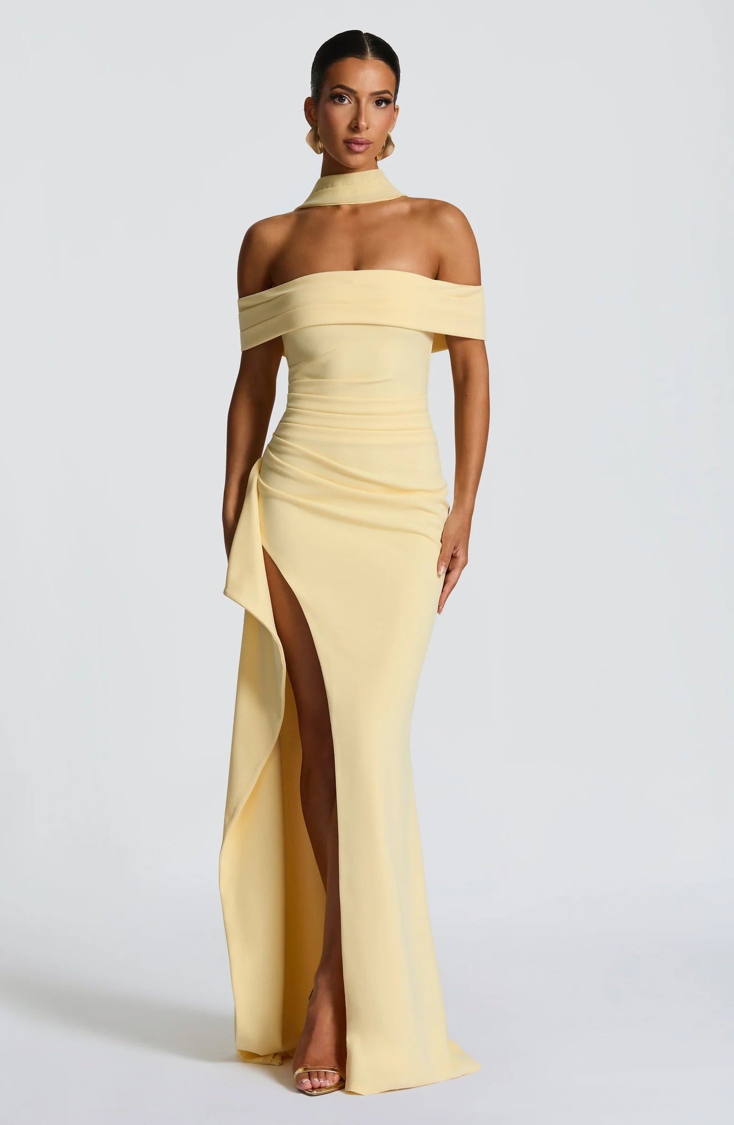 Front view of pale yellow off shoulder maxi dress with high slit and fitted formal silhouette