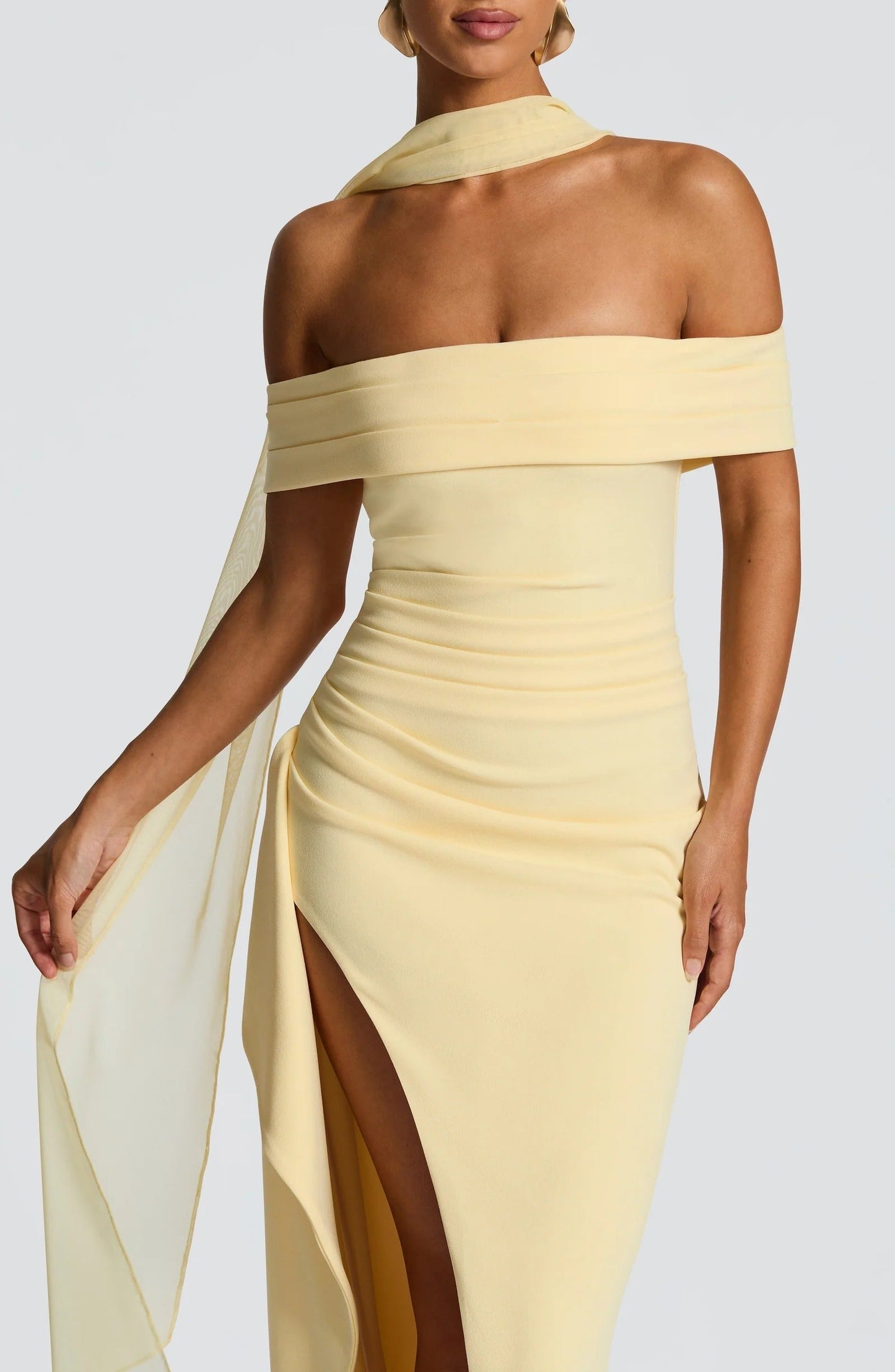 Close up of pale yellow off shoulder maxi dress showing draped neckline and thigh slit detail