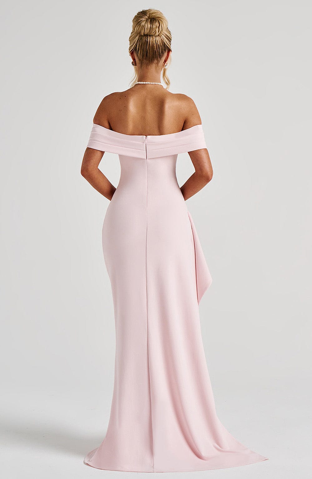 Three-quarter view of pale pink formal dress with off shoulder neckline and high leg slit
