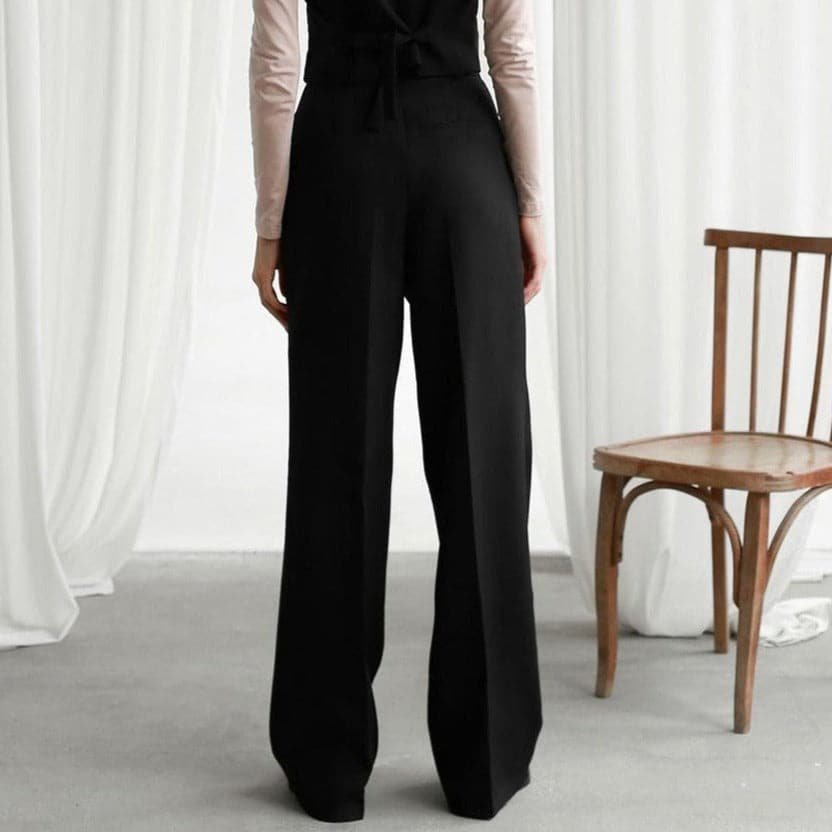 Back view of black high waisted wide leg linen pants with a tailored loose fit