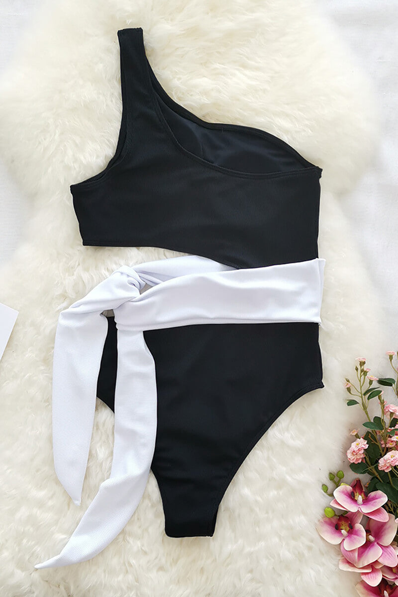 Black one shoulder one piece swimsuit with pink leopard print wrap tie on woven mat