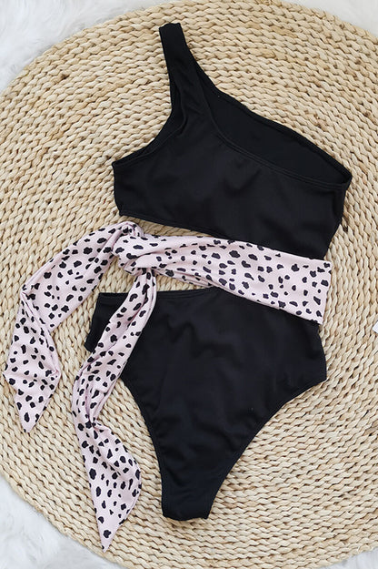 Blue one shoulder one piece swimsuit with pink waist tie and side cutout flat lay