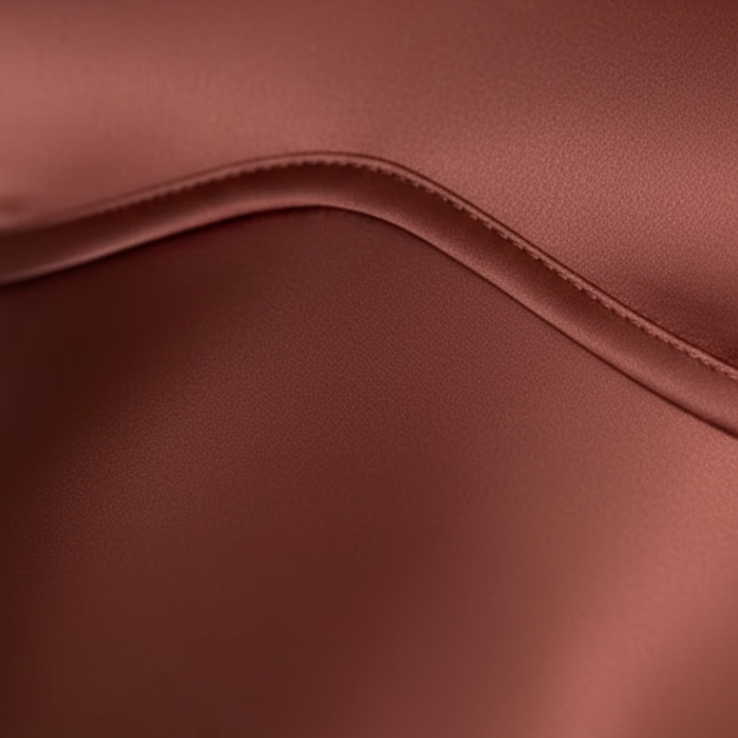 Close-up of rust satin maxi dress fabric showing smooth sheen and curved seam detail