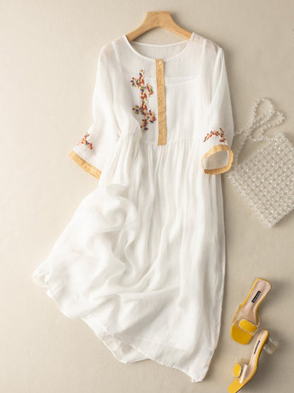 White women's summer embroidered midi dress with tan trim and sheer flowing skirt