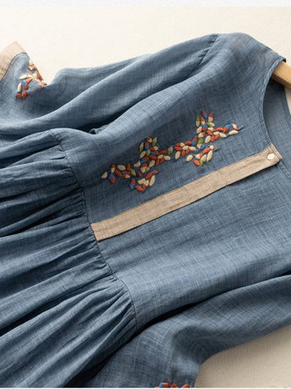 Close-up of blue embroidered midi dress with floral chest stitching and gathered waist