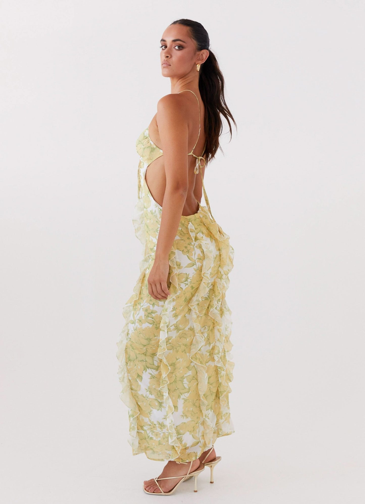 Side view of floral maxi dress with open back, thin straps, and flowing ruffle details