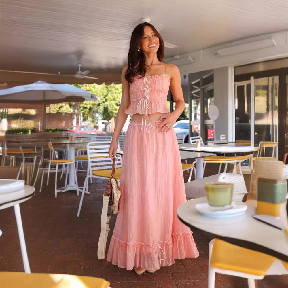 Pink summer maxi skirt set with ruched crop top and flowing skirt in a cafe setting