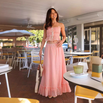Pink summer maxi skirt set with ruched crop top and flowing skirt in a cafe setting