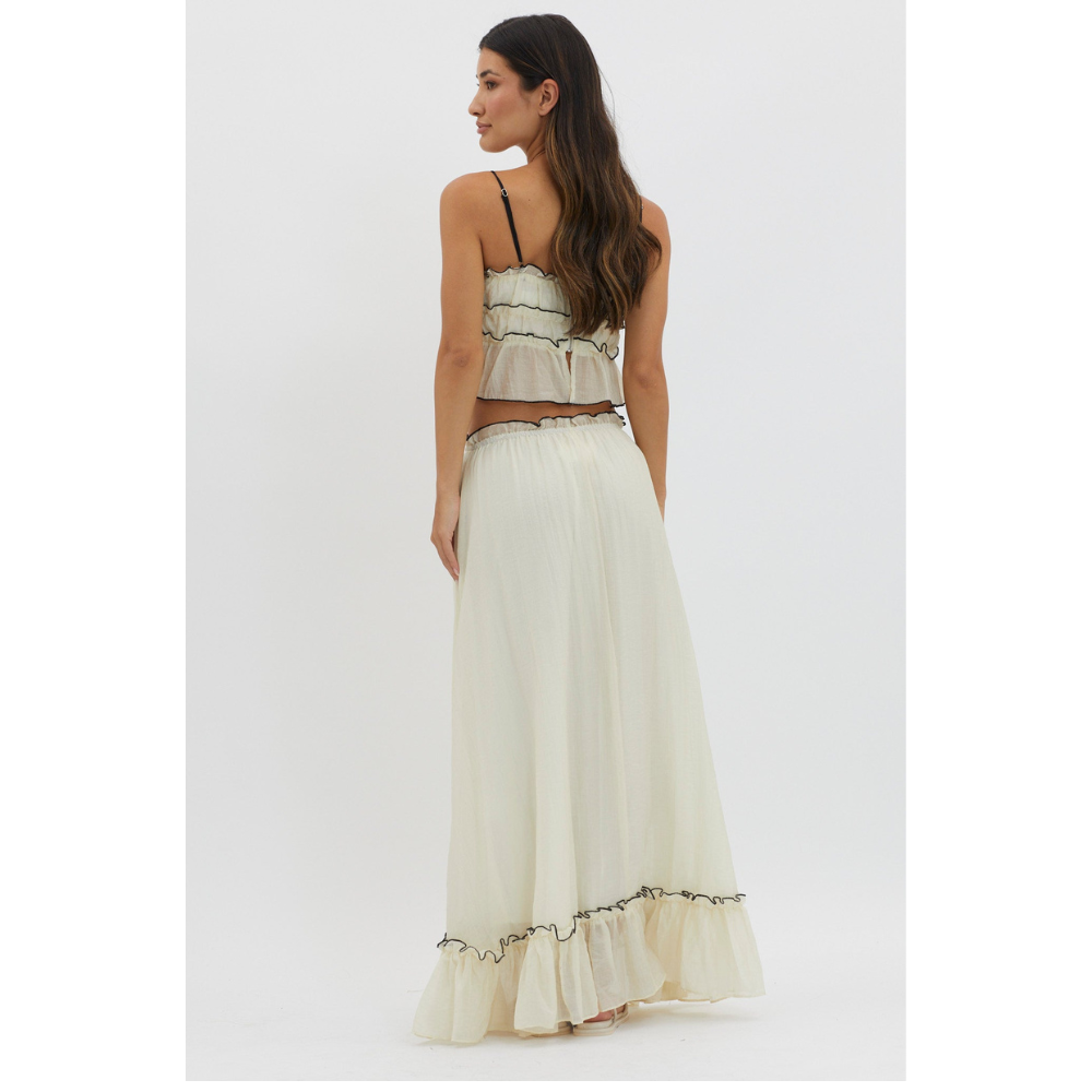 Back view of cream summer maxi skirt set with black trim and ruffled hem on white background