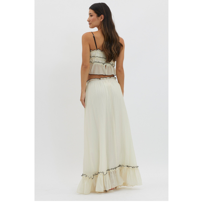 Back view of cream summer maxi skirt set with black trim and ruffled hem on white background