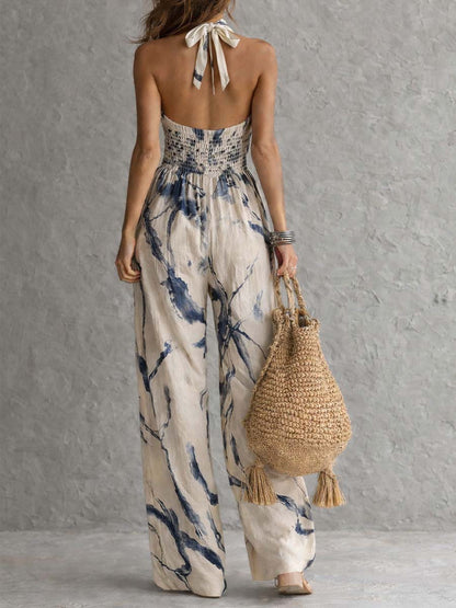 Back view of cream navy printed halter jumpsuit with smocked waist and wide leg pants