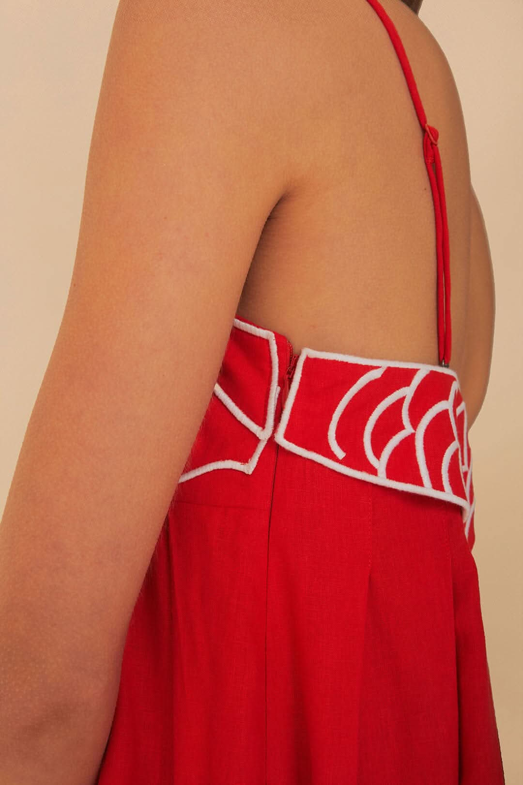 Close-up of red fish print maxi dress showing open back, thin strap, and scalloped trim