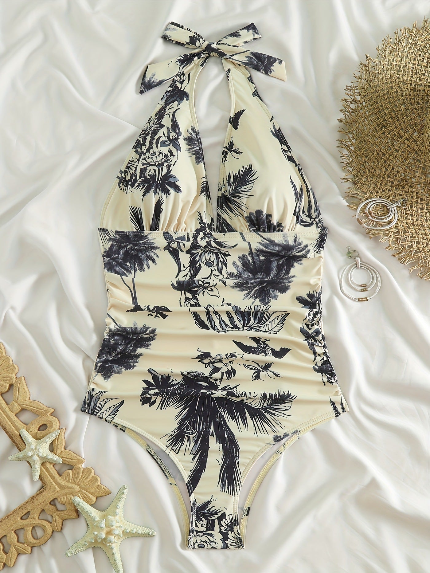 Flat lay tropical one piece swimsuit with halter neck tie and black palm print on cream fabric