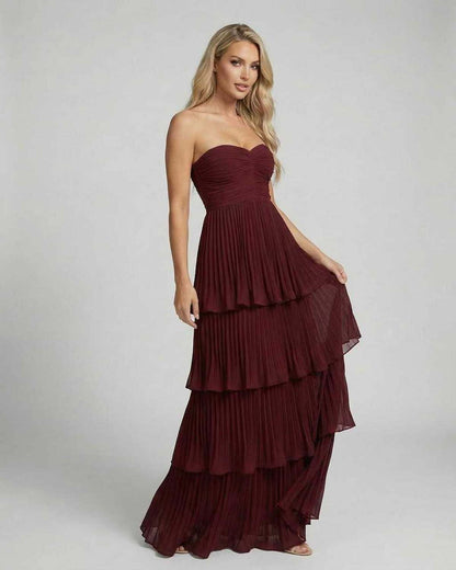 Burgundy strapless wedding guest dress with fitted bodice and tiered maxi hem