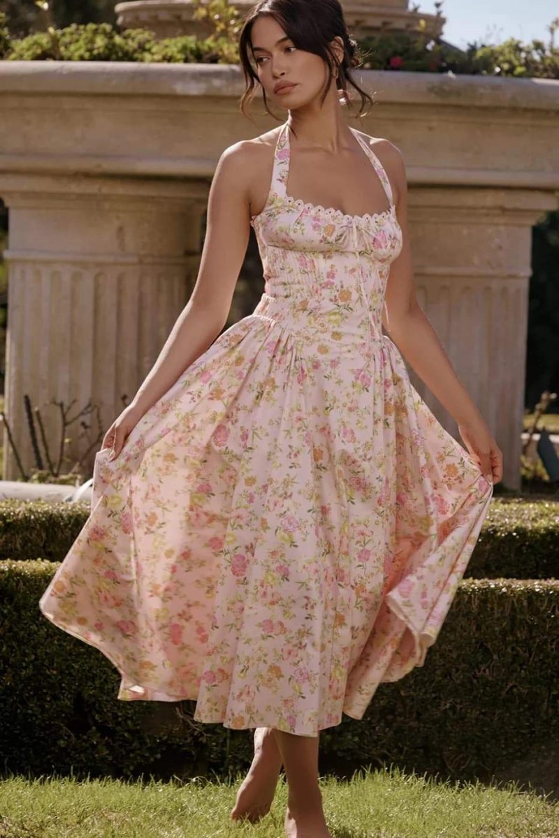 Front view of a pink floral halter midi dress with ruched bodice and flowy skirt
