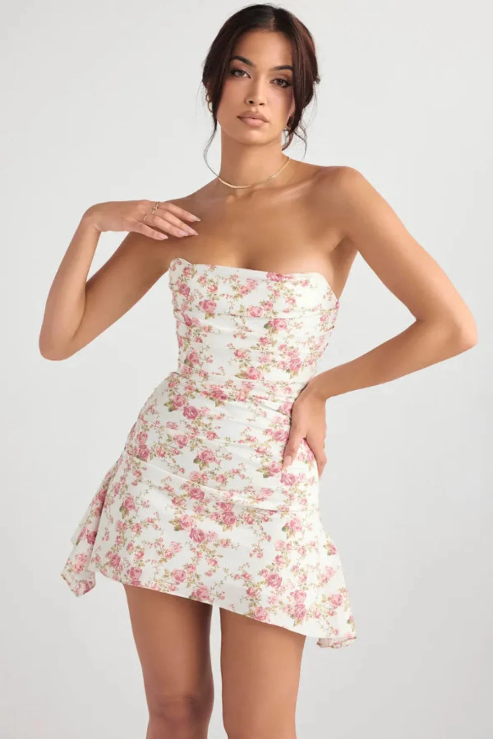 Front view of a floral mini dress with strapless neckline, fitted waist, and flowing side panel