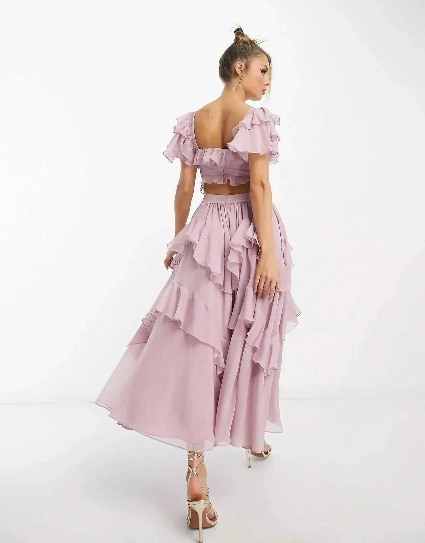Side view of blush pink midi dress showing off-shoulder ruffles and cascading layered skirt