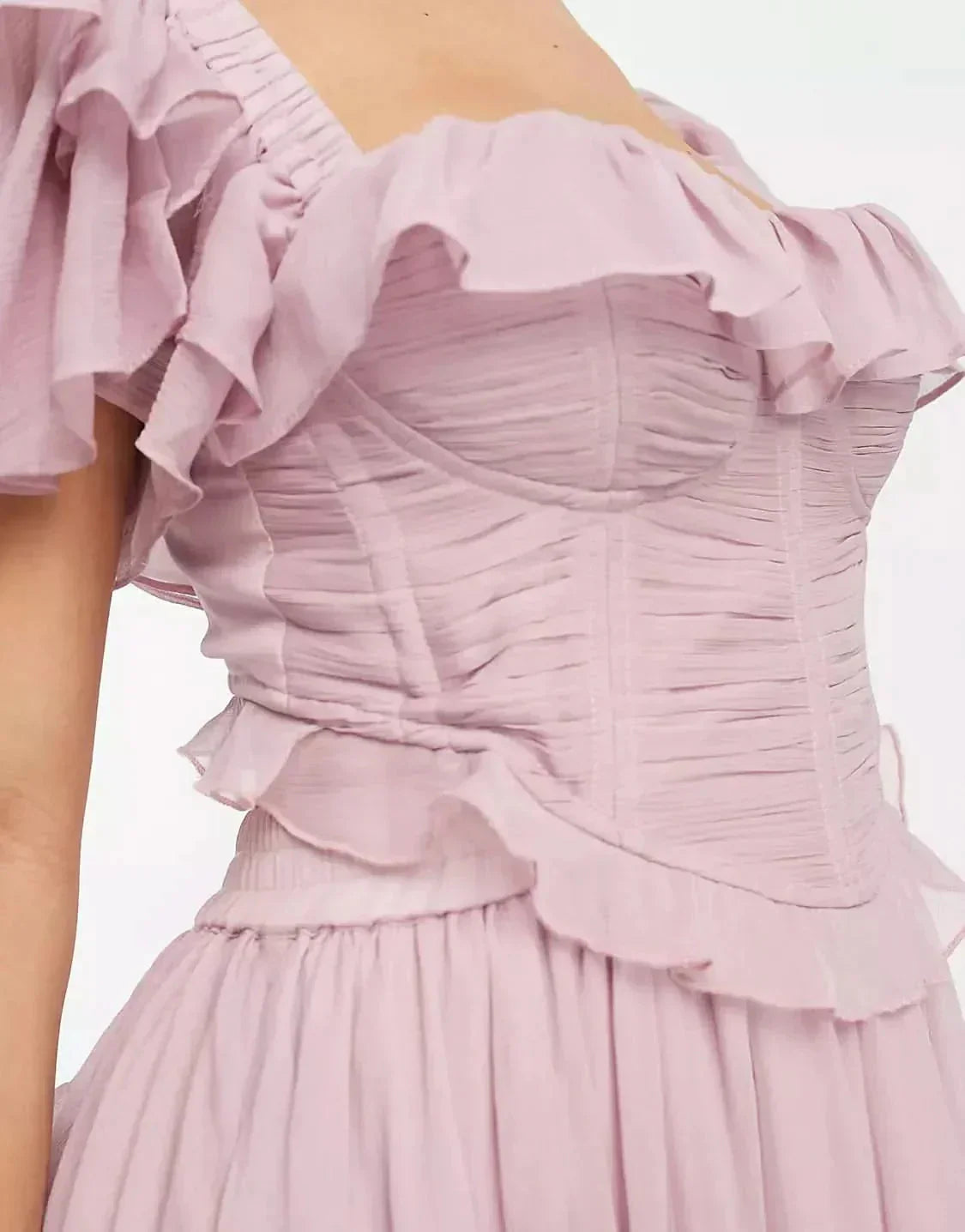 Back view of blush pink wedding guest dress with open back, ruffled sleeves, and full midi skirt