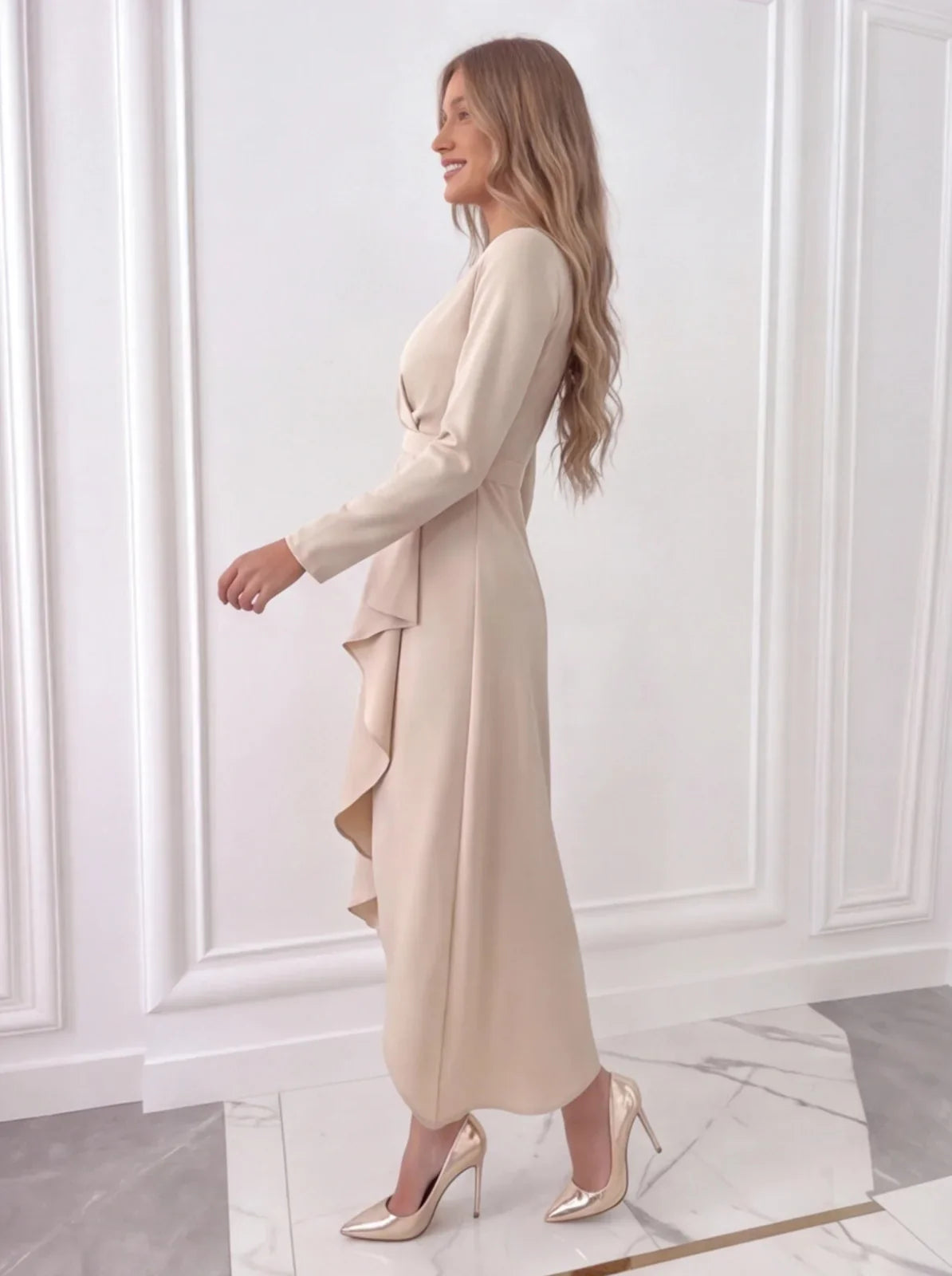 Side view of beige women's wedding guest wrap midi dress with flowing skirt and long sleeves